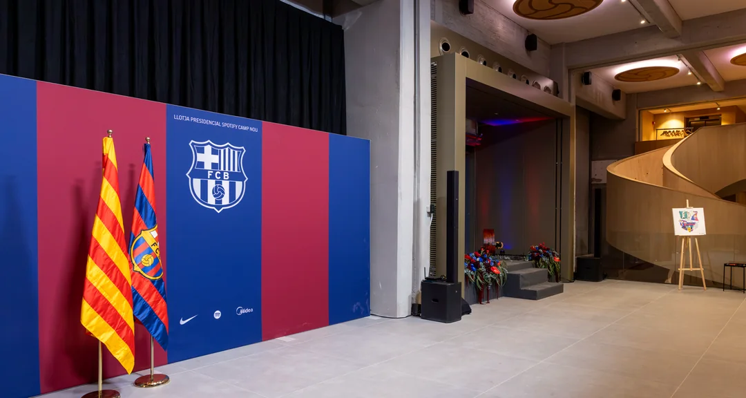 The Llotja Presidencial set for match day: Casa Très photocall with the Club crest and flags, florals by the stage and a live-painting easel by the spiral staircase
