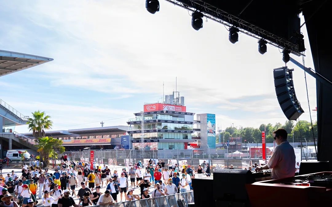 View from the Fan Zone main stage: lighting rig, line-array speakers and the DJ, with the crowd and the Circuit’s control tower beyond